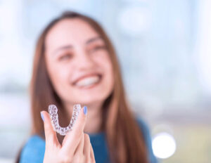 women holding Invisalign® while smiling in background