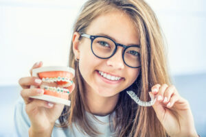Orthodontics invisible braces or silicone trainer in the hands of a young smiling girl