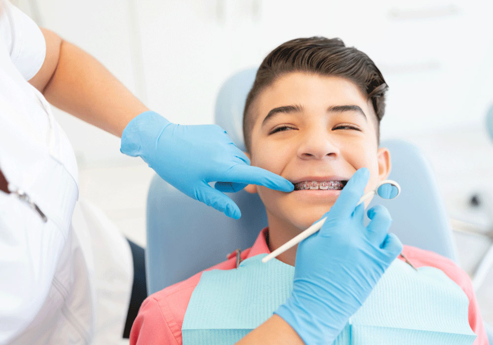 child smiling in dentist chair with dentist examining teeth